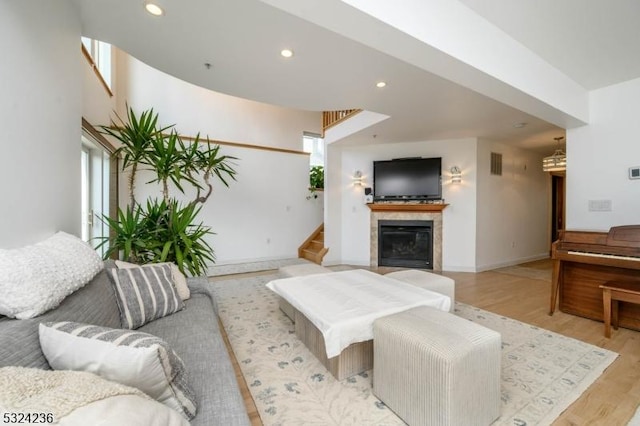 living room with stairway, a healthy amount of sunlight, light wood-style floors, and a glass covered fireplace