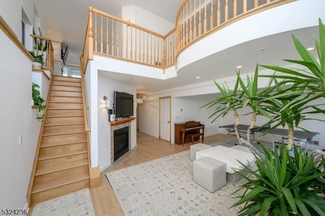 living room with a fireplace, stairway, wood finished floors, and a high ceiling