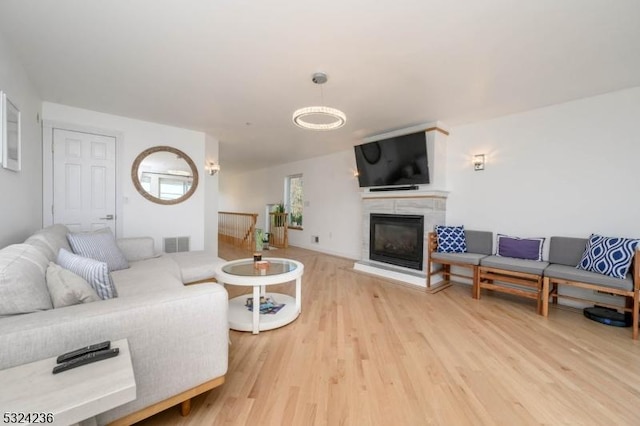 living area with a glass covered fireplace, wood finished floors, and visible vents