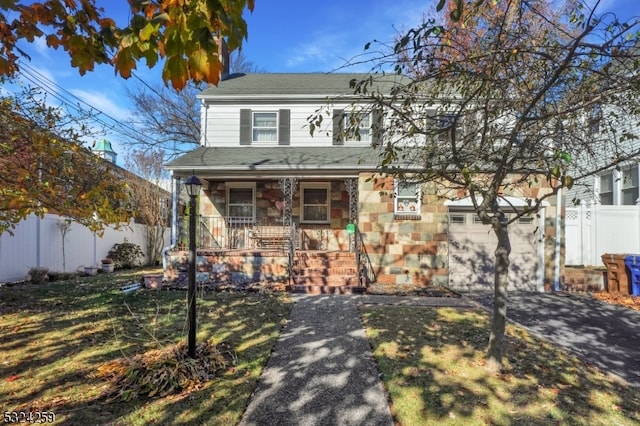 view of front of home featuring covered porch, a garage, and a front yard