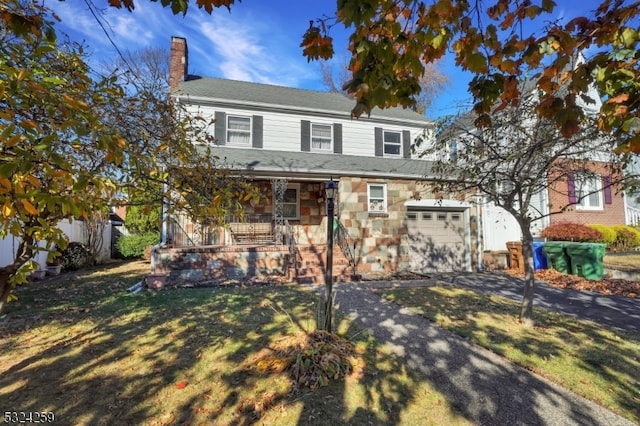 view of front of home with covered porch, a front yard, and a garage