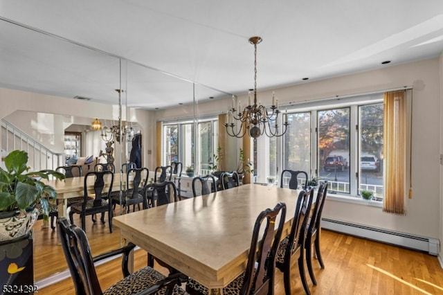 dining space featuring light wood-type flooring, baseboard heating, and an inviting chandelier