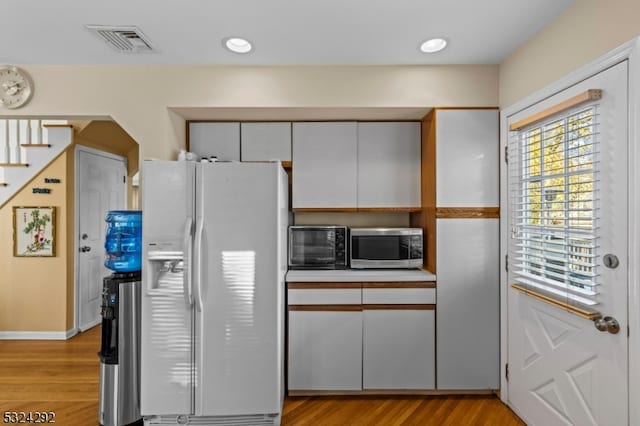 kitchen featuring white cabinetry, light wood-type flooring, and white refrigerator with ice dispenser