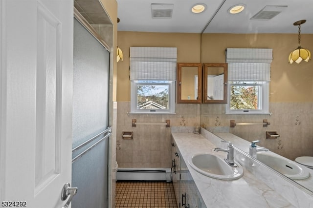 bathroom featuring baseboard heating, plenty of natural light, and tile walls