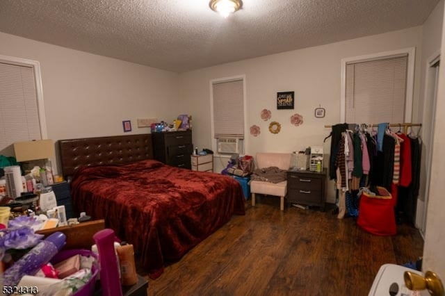 bedroom with a textured ceiling, cooling unit, and dark hardwood / wood-style floors