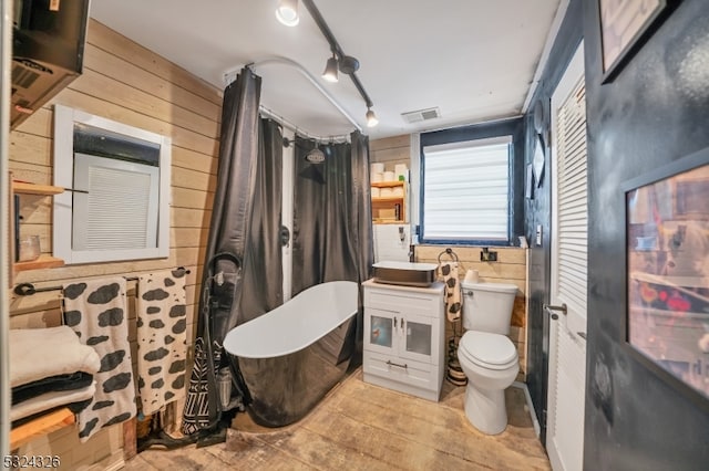 bathroom featuring wood walls, toilet, a bathtub, and sink