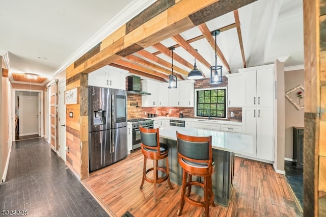 kitchen with stainless steel appliances, wall chimney range hood, white cabinetry, and a kitchen island