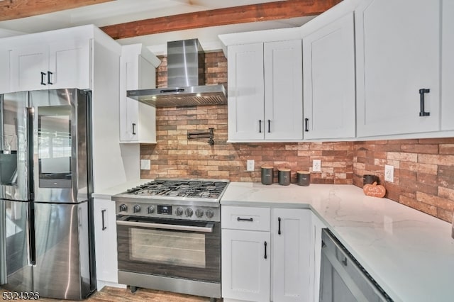 kitchen featuring white cabinetry, wall chimney range hood, appliances with stainless steel finishes, and tasteful backsplash