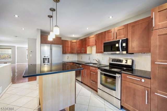 kitchen featuring pendant lighting, a center island, decorative backsplash, light wood-type flooring, and appliances with stainless steel finishes