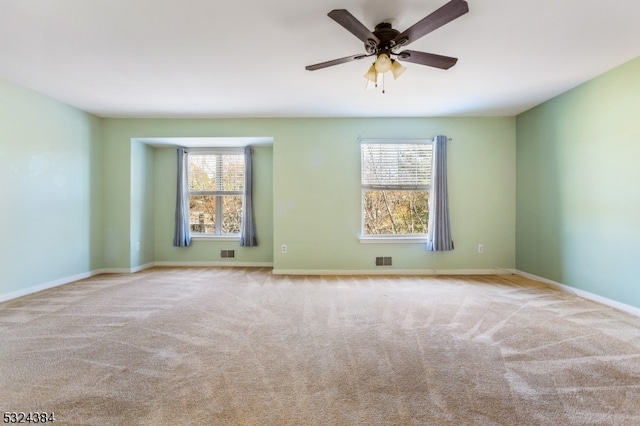 unfurnished room with ceiling fan, light colored carpet, and a healthy amount of sunlight