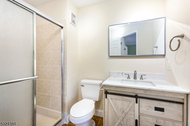 bathroom with tile patterned floors, vanity, toilet, and a shower with door