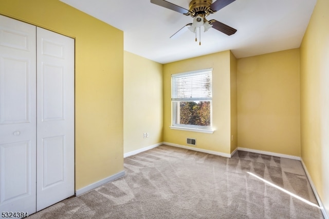 unfurnished bedroom featuring ceiling fan, light colored carpet, and a closet