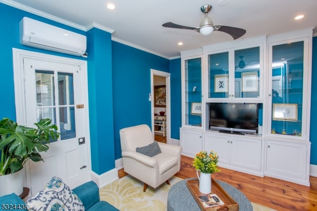 living room with a wall mounted air conditioner, ceiling fan, light wood-type flooring, and crown molding