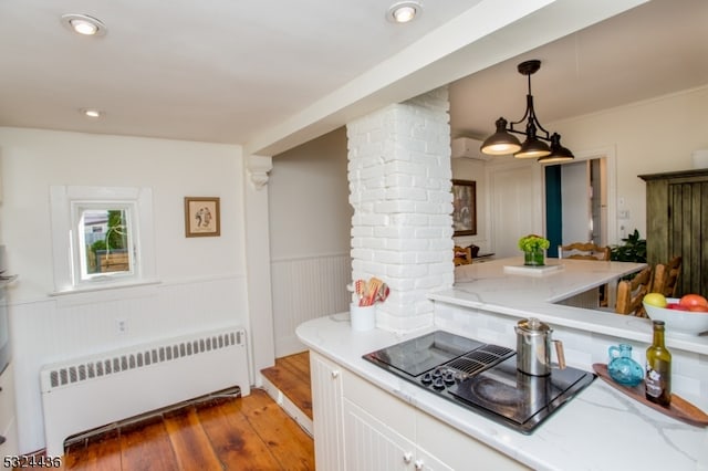 kitchen featuring decorative columns, dark wood-type flooring, white cabinets, radiator heating unit, and hanging light fixtures