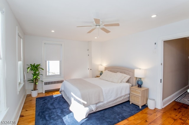 bedroom with radiator heating unit, hardwood / wood-style flooring, and ceiling fan