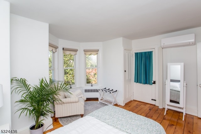 bedroom featuring hardwood / wood-style flooring, radiator, and a wall mounted AC