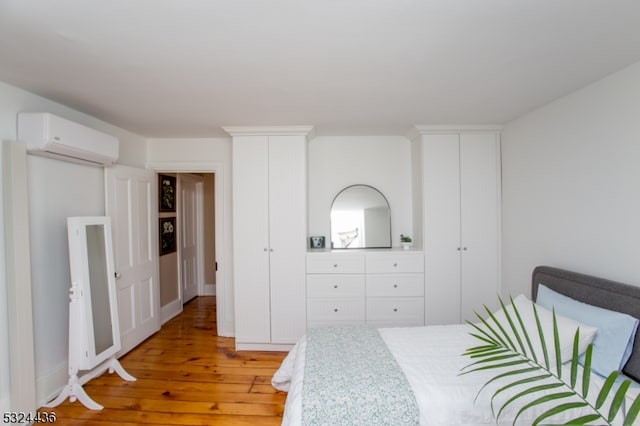 bedroom featuring a wall mounted AC and light hardwood / wood-style flooring