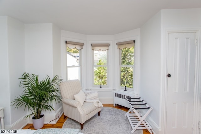 sitting room featuring radiator heating unit, plenty of natural light, and wood-type flooring