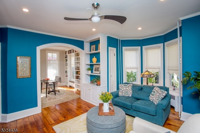 living room with radiator, ceiling fan, wood-type flooring, and ornamental molding