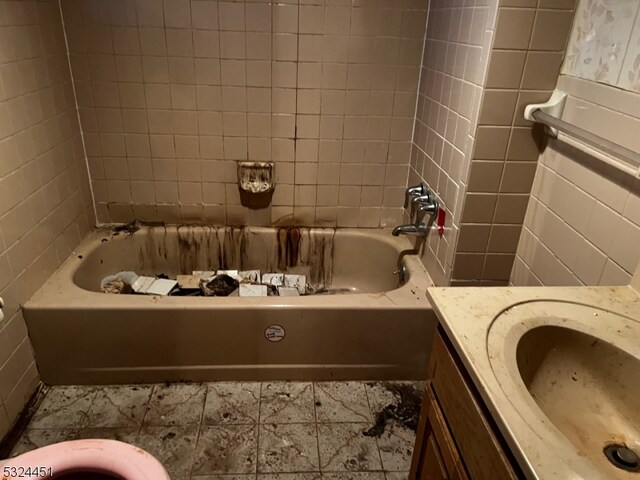 bathroom featuring shower / bathtub combination, vanity, and tile walls