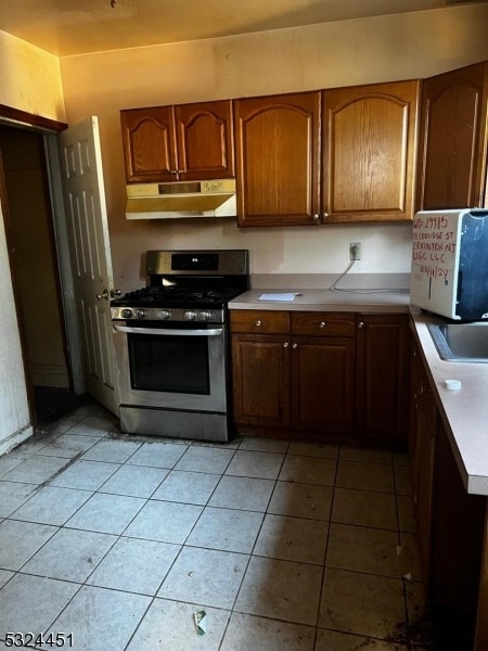 kitchen featuring gas range, sink, and light tile patterned floors