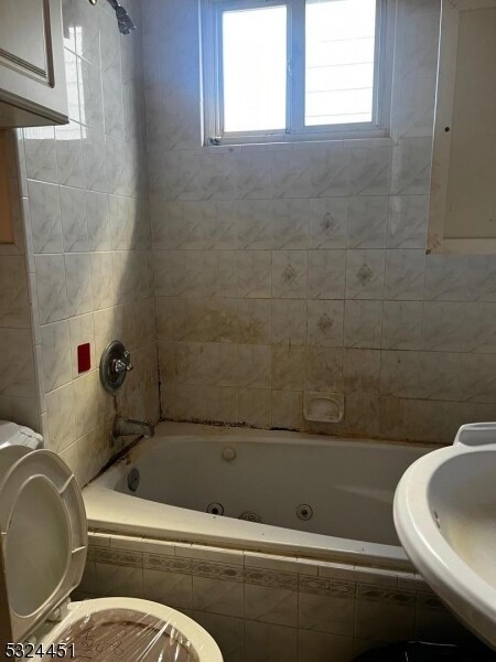 bathroom featuring plenty of natural light, tiled shower / bath combo, and toilet