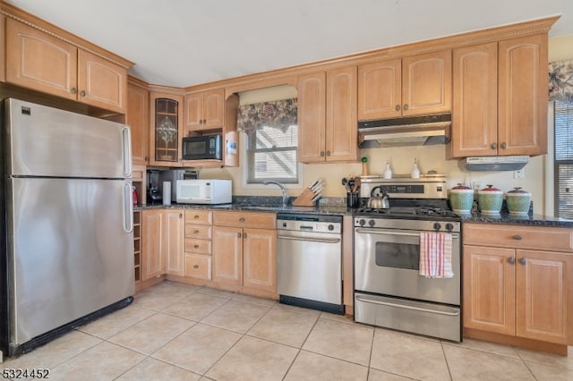 kitchen with light tile patterned flooring, sink, stainless steel appliances, and dark stone countertops