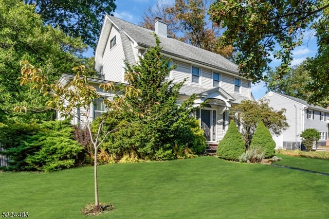 colonial house featuring central air condition unit and a front yard