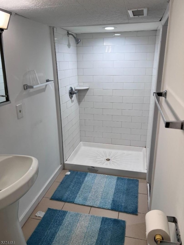 bathroom featuring tile patterned flooring, tiled shower, and a textured ceiling