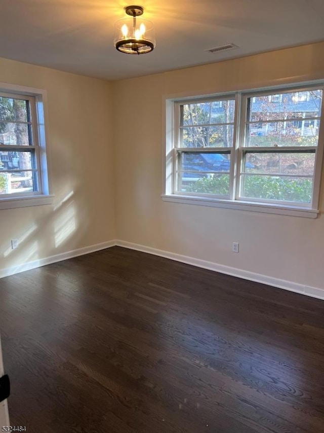 empty room featuring dark hardwood / wood-style floors and a notable chandelier