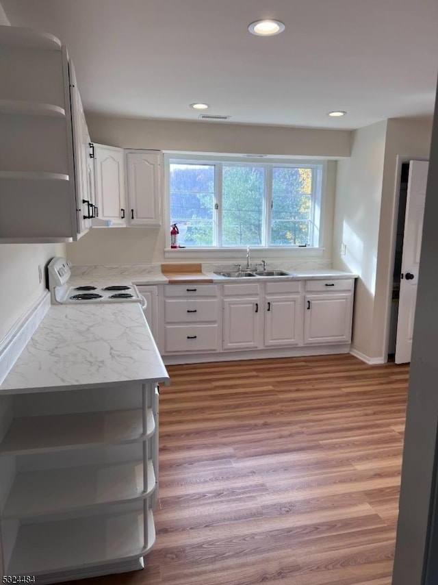 kitchen with sink, light stone countertops, light wood-type flooring, white range oven, and white cabinetry