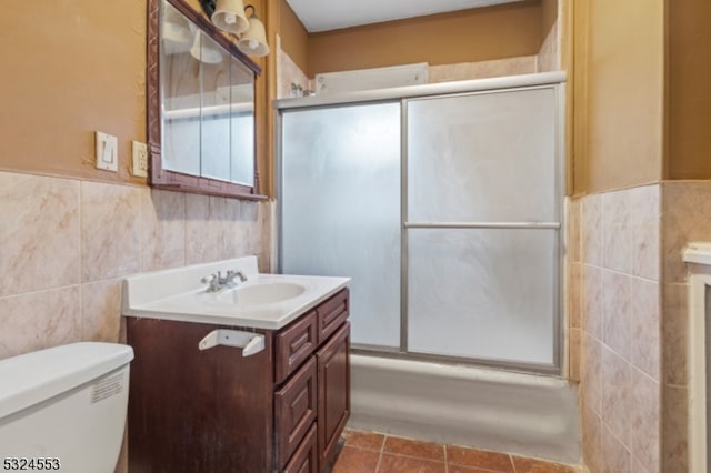 full bathroom with tile patterned floors, vanity, bath / shower combo with glass door, and tile walls