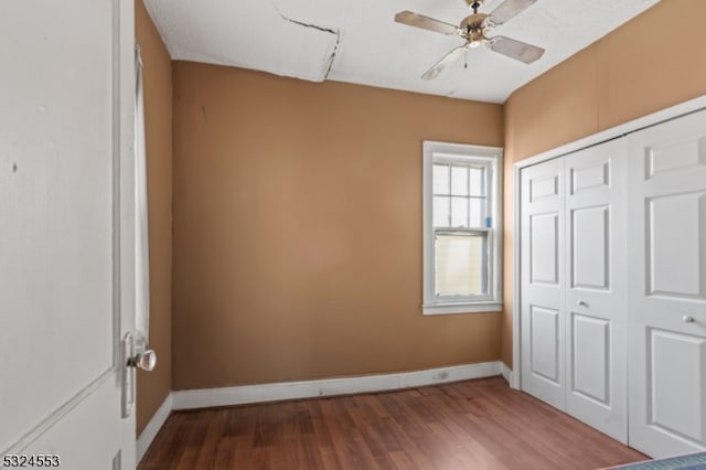 unfurnished bedroom with ceiling fan, dark wood-type flooring, and a closet