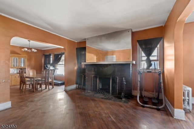 living room featuring plenty of natural light, a fireplace, dark wood-type flooring, and an inviting chandelier