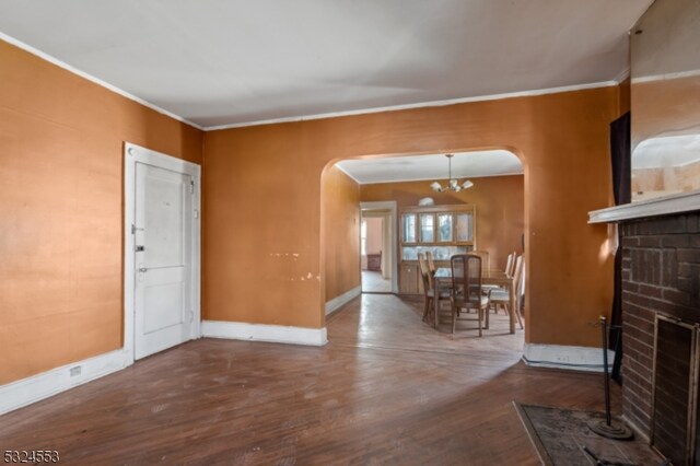 living room with hardwood / wood-style floors, a notable chandelier, crown molding, and a fireplace