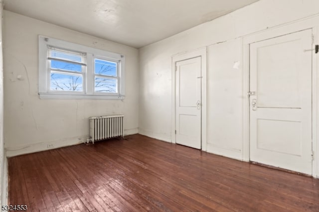 unfurnished bedroom featuring radiator and dark hardwood / wood-style floors