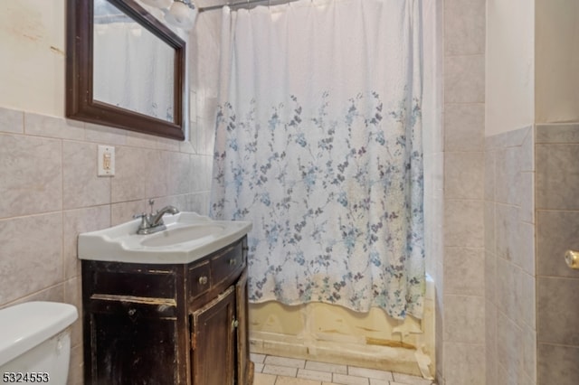 bathroom with a shower with shower curtain, vanity, toilet, and tile walls