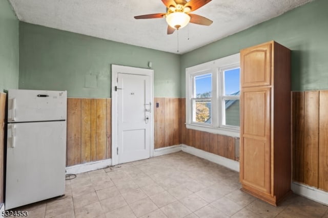 kitchen featuring wooden walls, ceiling fan, a textured ceiling, and white refrigerator