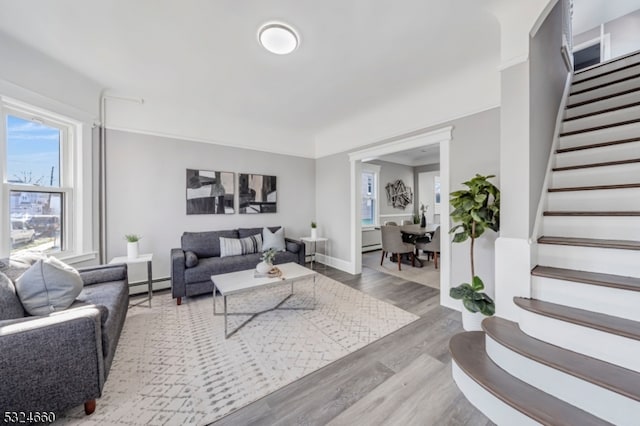 living room with a baseboard heating unit and light hardwood / wood-style flooring