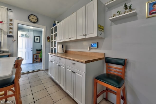 kitchen with butcher block countertops, white cabinets, and light tile patterned floors