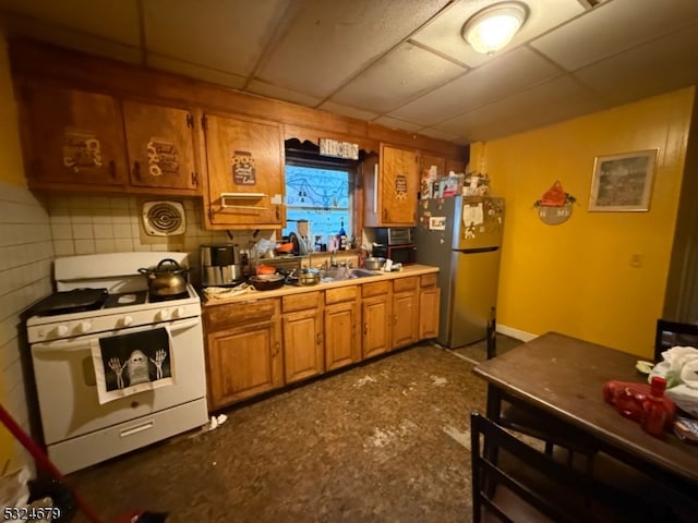 kitchen with stainless steel fridge, white gas range oven, and a drop ceiling