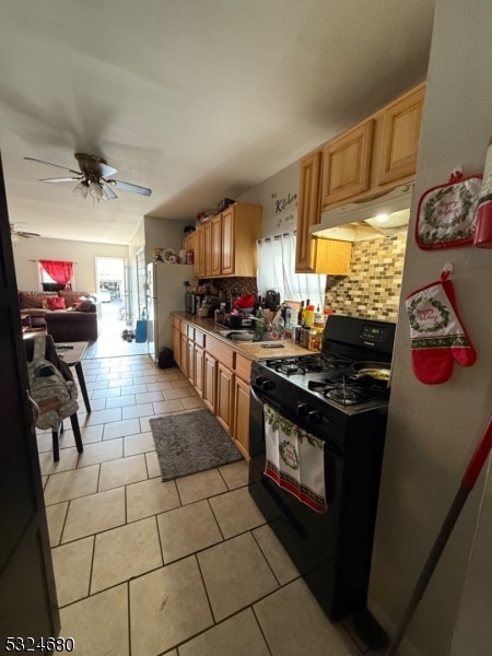 kitchen with tasteful backsplash, black range with gas stovetop, ceiling fan, light tile patterned floors, and white fridge