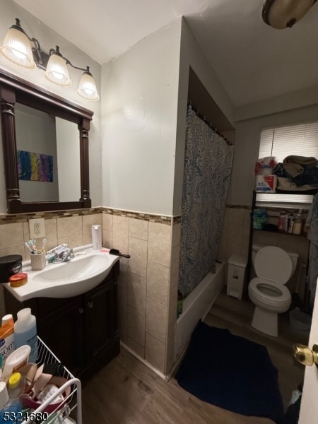 bathroom featuring a shower with curtain, hardwood / wood-style floors, toilet, vanity, and tile walls