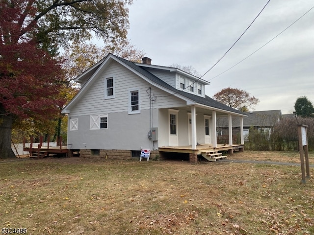 rear view of house with a lawn and a porch