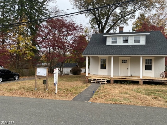 view of front of house with a porch, a shed, and a front yard