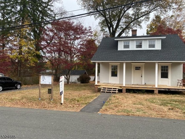 view of front of house featuring covered porch, a front lawn, and a storage shed