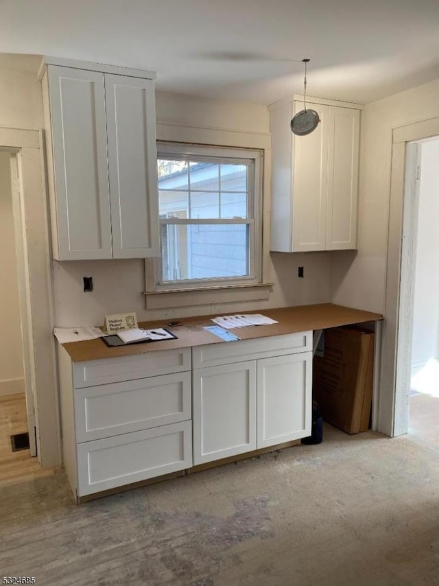 kitchen with white cabinets, light hardwood / wood-style floors, and hanging light fixtures