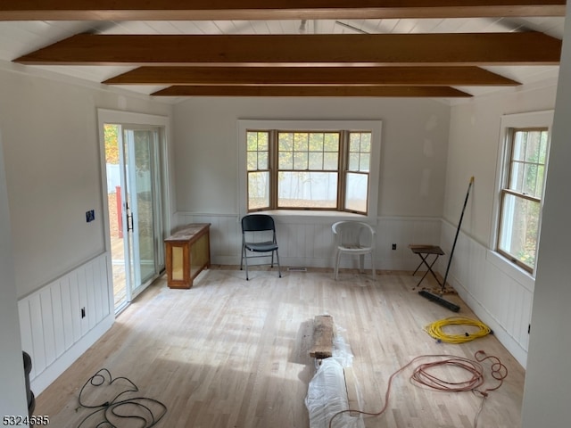 unfurnished room featuring a wealth of natural light, light hardwood / wood-style flooring, and lofted ceiling with beams