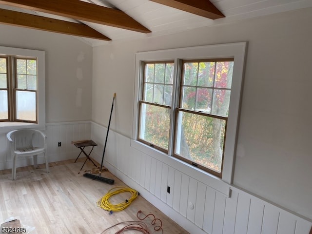 unfurnished room featuring lofted ceiling with beams, light hardwood / wood-style flooring, and a wealth of natural light