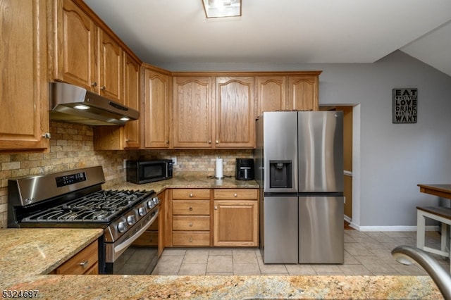 kitchen featuring stainless steel appliances, light stone counters, backsplash, vaulted ceiling, and light tile patterned flooring